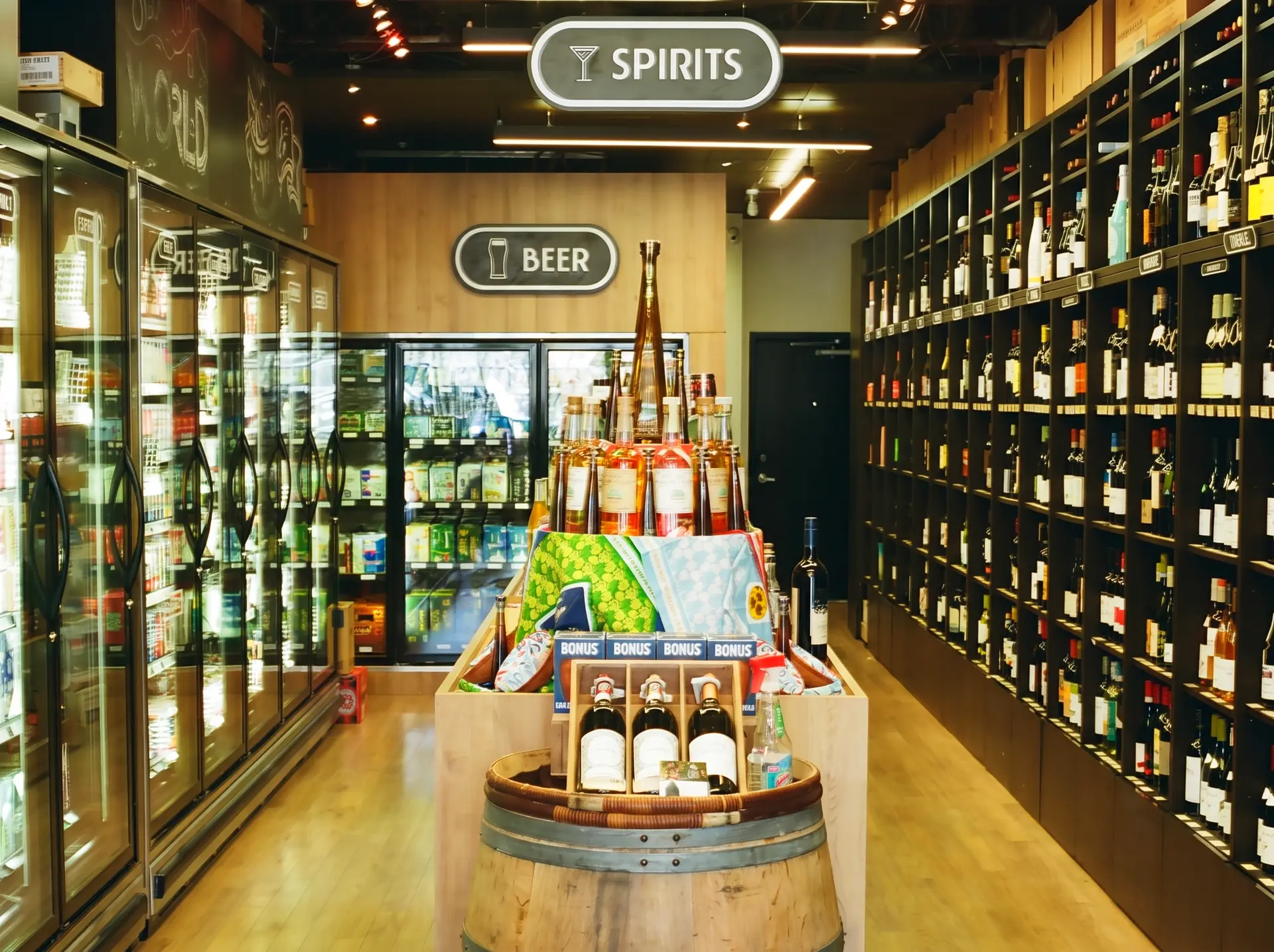 Inside Broadway Beer Wine & Spirits: the spirits wall, the beer fridges and a barrel display